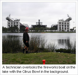 A technician overlooks the fireworks boat on the lake with the Citrus Bowl in the background